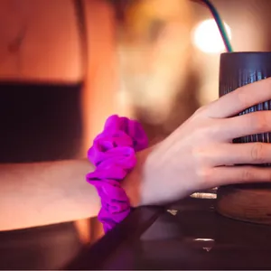 Coletero Tailsip fucsia en la muñeca de una chica con una copa